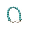 Turquoise beaded bracelet with an infinity charm on a textured surface
